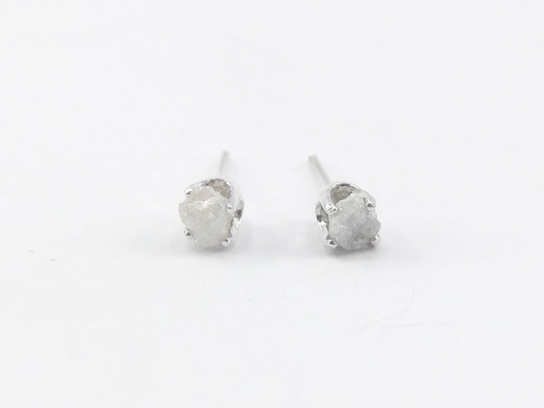 May include: A pair of silver stud earrings with rough, white diamond stones.
