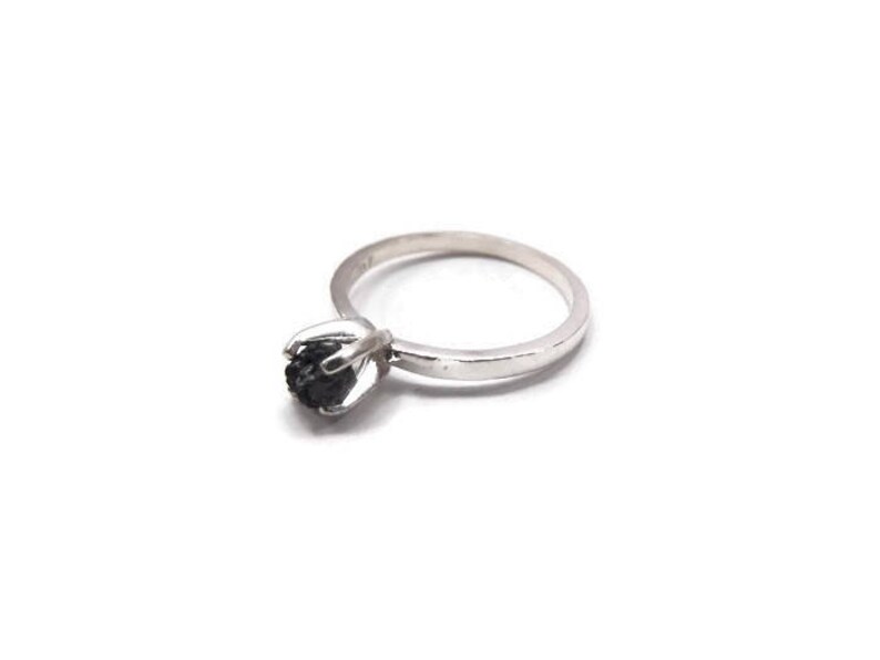 May include: A silver ring with a black gemstone set in a flower-shaped design.