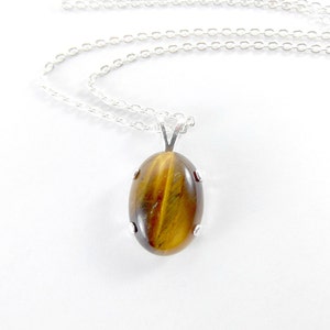 May include: A silver chain necklace with a brown and gold oval tiger's eye gemstone pendant.
