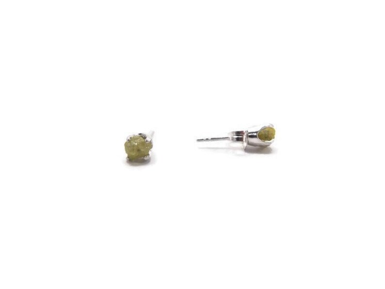 May include: A pair of silver stud earrings with small, rough, green gemstones.