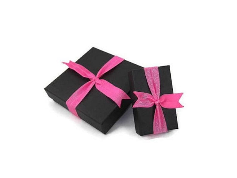 May include: Two black gift boxes with pink ribbon bows. The larger box is slightly larger than the smaller box.