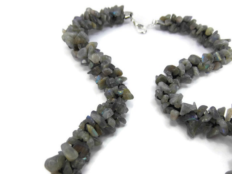 May include: A necklace made of gray labradorite gemstone chips. The chips are irregular in shape and size, and they are strung together on a silver chain.