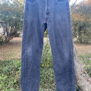 May include: A pair of dark blue denim jeans with a button fly and five pockets.