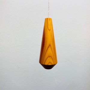 Könnte beinhalten: Ein Holz-Lichtschalter in Tropfenform mit natürlicher Holzoptik.