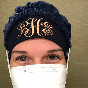 Pu&ograve; includere: Un berretto da lavoro blu navy con un elastico bianco e un monogramma ricamato in oro "BHG". Il berretto &egrave; indossato da una persona che indossa una maschera facciale bianca.
