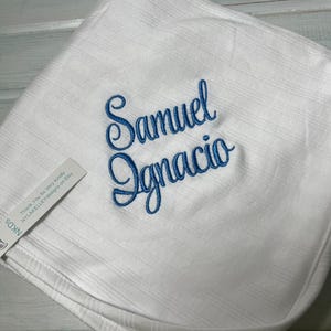 May include: White baby blanket with blue embroidered lettering that reads "Samuel Ignacio".