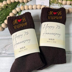 May include: A pair of brown socks with a personalized embroidered message. The socks have a red heart and the text "M&B 5/5/2018 Happy 7th Anniversary".