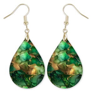 May include: A pair of teardrop earrings with a gold-colored hook. The earrings feature a green and gold abstract design. The design has shades of green and gold with a marbled effect.