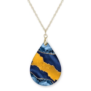 May include: A gold chain necklace with a teardrop-shaped pendant. The pendant is made of blue and gold resin with a marbled effect.