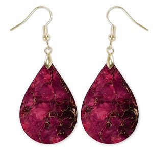 May include: A pair of teardrop earrings with a vibrant magenta and gold marbled design. The earrings have gold-colored fish hook ear wires and a gold-colored cap at the top of the teardrop. The earrings are a stylish accessory.