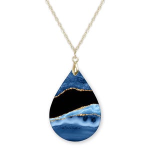May include: A gold chain necklace with a teardrop-shaped pendant. The pendant is made of blue resin with gold glitter accents and a black background.