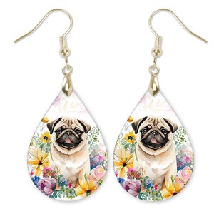 May include: Teardrop-shaped earrings featuring a watercolor illustration of a pug dog surrounded by colorful flowers. The earrings have gold-colored hooks. The pug is light brown with a black muzzle and is set against a white background.