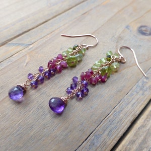 May include: A pair of dangle earrings featuring a cascade of green, pink, and purple gemstones. The earrings are crafted with rose gold wire and have a delicate, feminine design.