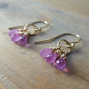 May include: Gold earrings with a cluster of three pink gemstone drops.