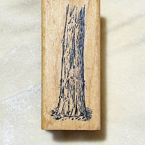 May include: A wooden stamp with a black and white illustration of a tree trunk.