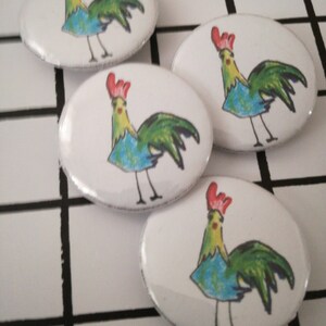 May include: Four white oval-shaped buttons with a colorful cartoon rooster illustration on each. The roosters are drawn in a whimsical style with blue, green, and yellow colors.