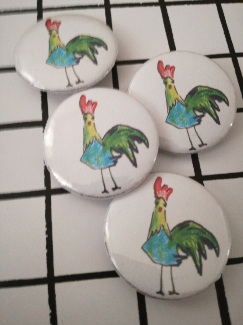 May include: Four white oval-shaped buttons with a colorful cartoon rooster illustration on each. The roosters are drawn in a whimsical style with blue, green, and yellow colors.