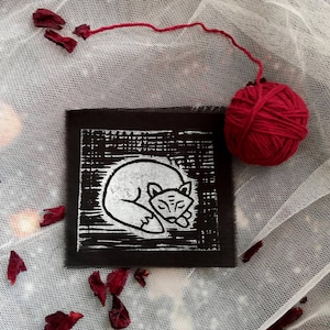 以下が含まれることがあります： 黒い背景に寝ているキツネの白黒の版画。プリントは白い枠で囲まれています