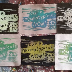 May include: Six fabric patches with the text "Cure neurotypicals NOW!" printed in black, white, green, and blue ink. Each patch features a small mushroom graphic.