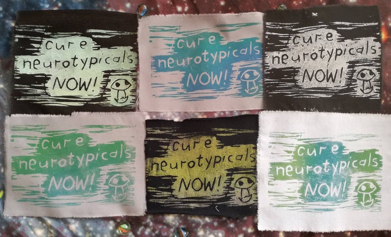 May include: Six fabric patches with the text "Cure neurotypicals NOW!" printed in black, white, green, and blue ink. Each patch features a small mushroom graphic.