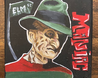 May include: A hand-painted canvas featuring a portrait of Freddy Krueger, the iconic horror character from the Nightmare on Elm Street franchise. He is depicted wearing a green and red striped sweater, a brown fedora, and a menacing expression. The background is black with the words "Nightmare" written in red.
