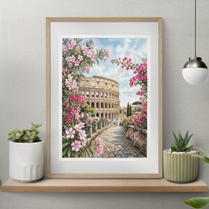 Peut inclure: Une impression encadrée à l'aquarelle du Colisée à Rome, en Italie, entourée de plantes à fleurs roses et rouges. L'œuvre est exposée sur une étagère en bois avec des plantes en pot, contre un mur neutre.
