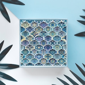 May include: A blue and white patterned box with a geometric design. The box is surrounded by green palm leaves on a white and blue background.