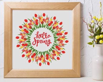 May include: A framed cross-stitch embroidery with a wreath of red, yellow, and green tulips and the text "hello spring" in red lettering.