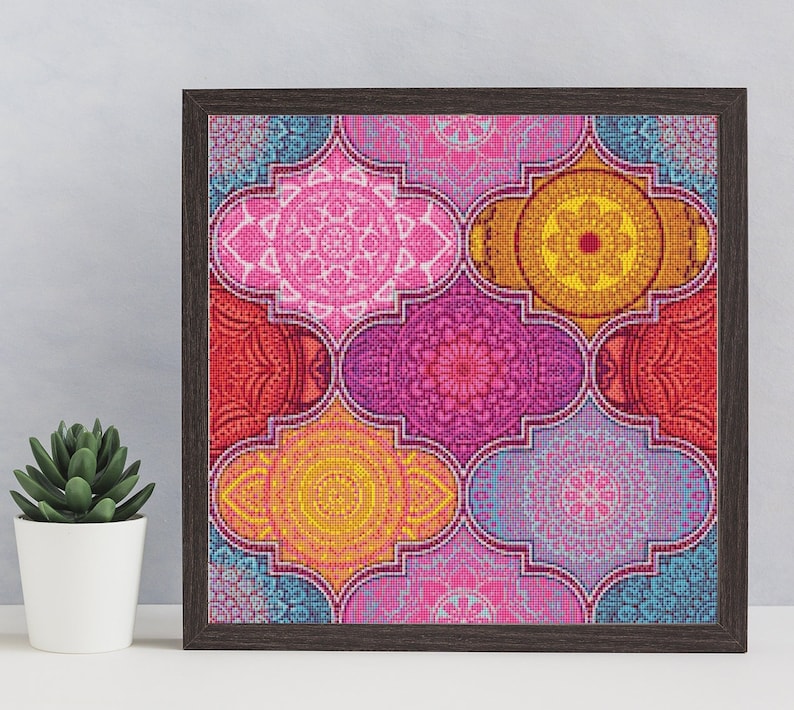 May include: A framed print with a colorful geometric pattern. The design features a variety of pink, red, yellow, and blue mandala-like shapes.