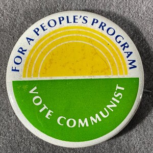 May include: A round button with a white border, featuring the text "FOR A PEOPLE'S PROGRAM" in blue, and "VOTE COMMUNIST" in white on a green background. The top half has a yellow sun design.