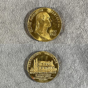 May include: Two gold-colored commemorative coins. The top coin features a profile of George Washington and the text "George Washington Bicentennial 1732 1932." The bottom coin depicts a building and reads "Washington's Birthplace Wakefield" and other text.