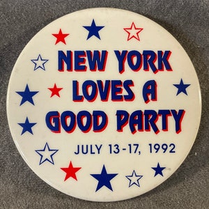 May include: A white button with blue and red stars and the text "NEW YORK LOVES A GOOD PARTY JULY 13-17, 1992".