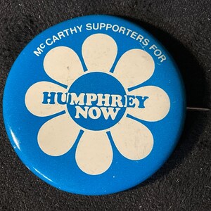 May include: A blue and white button with a daisy design and the text "McCarthy Supporters for Humphrey Now".