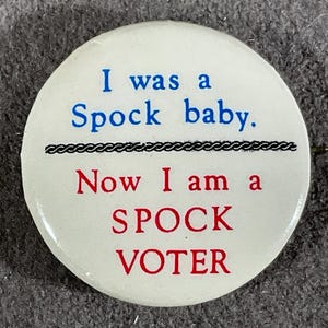 May include: White circular button with the text "I was a Spock baby. Now I am a Spock voter" in blue and red lettering. A black decorative line separates the phrases.