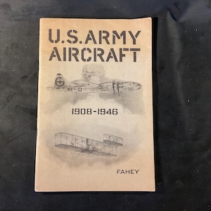 May include: A vintage book titled "U.S. Army Aircraft" with illustrations of airplanes. The cover is tan with black text and illustrations. The book's title and the years 1908-1946 are prominently displayed. The author's name, Fahey, is also visible.
