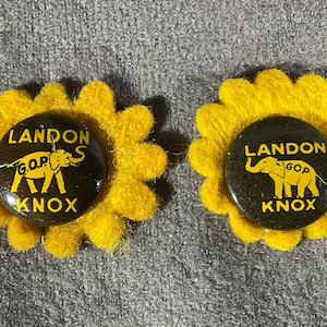 May include: Two circular black pinback buttons featuring yellow text that reads LANDON KNOX and a yellow elephant graphic with the letters G.O.P. Each button is mounted on a yellow felt flower-shaped backing with scalloped edges.