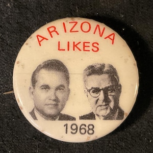 May include: A white button with the text "Arizona Likes 1968" in red. The button features black and white photos of two men.