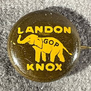 May include: A round political campaign button with a dark brown background and yellow text. The text reads LANDON at the top and KNOX at the bottom. In the center, a yellow elephant graphic features the letters GOP printed on its side.