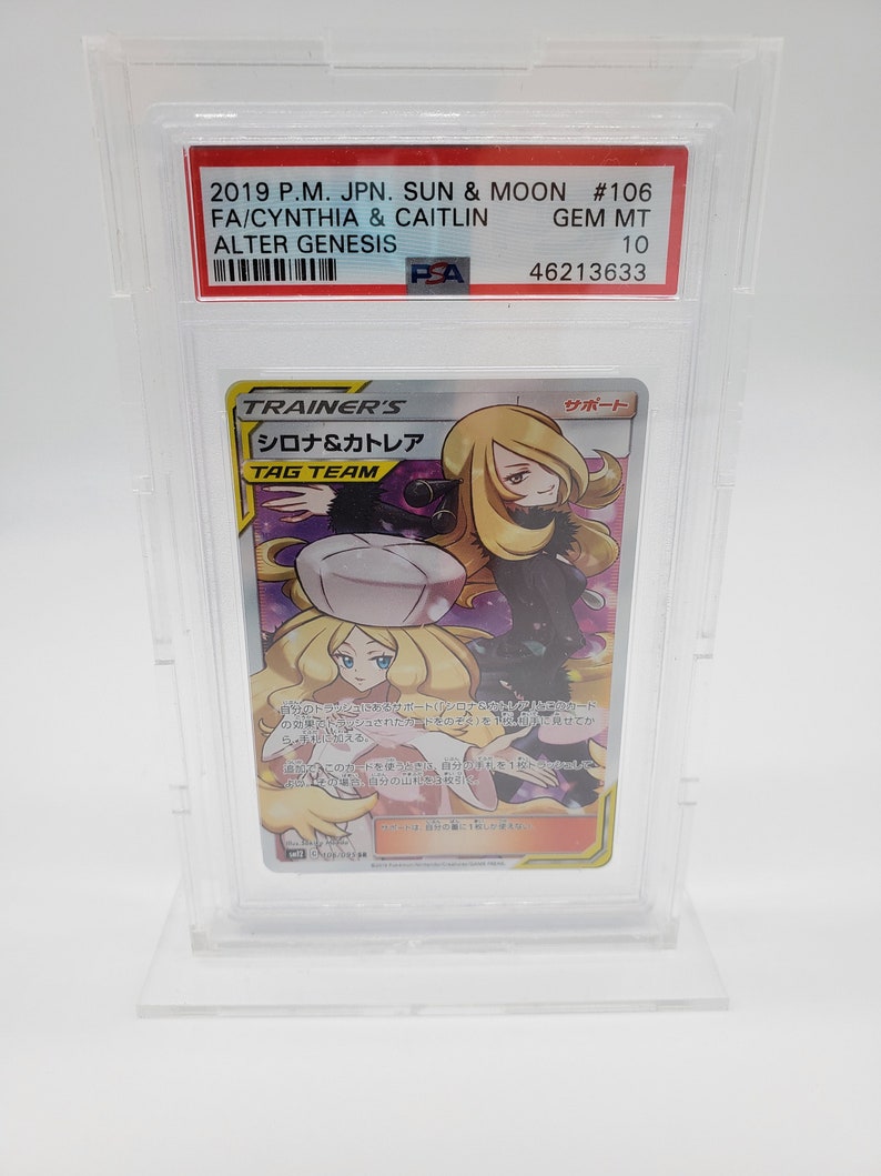 Puede incluir: Una carta de comercio de Pok&eacute;mon con Cynthia y Caitlin de la serie Sol y Luna. La carta est&aacute; calificada como Gem Mint 10 por PSA. La carta es una carta de Entrenador y es una carta de Equipo de Etiqueta. La carta es del set Alter Genesis.
