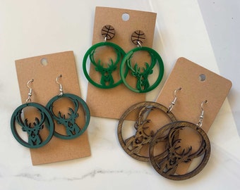 May include: Two pairs of earrings featuring a deer silhouette. One pair is green and the other is brown. Both pairs are made of wood and have a circular shape.