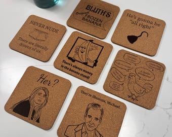 Puede incluir: Un conjunto de posavasos cuadrados de corcho con varios diseños y textos grabados. Los posavasos presentan frases como "BLUTH'S Original Frozen Banana" y "Never Nude". Otros diseños incluyen personajes de dibujos animados y citas. Una botella de vidrio azul con una flor roja en el fondo.