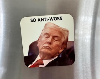 Puede incluir: Un imán rectangular con esquinas redondeadas. Presenta un retrato de un hombre con traje y corbata roja, con los ojos cerrados. El texto "SO ANTI-WOKE" está impreso en negro en la parte superior del imán.