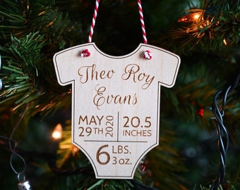 Puede incluir: Un adorno de madera en forma de body de bebé con el nombre Theo Roy Evans, la fecha 29 de mayo de 2020 y las estadísticas de nacimiento del bebé: 20,5 pulgadas y 6 libras 3 onzas.