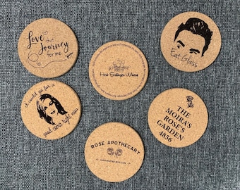 Puede incluir: Seis posavasos de corcho con diferentes diseños. Un posavasos presenta el texto "Love that journey for me" con un corazón y un avión de papel. Otro posavasos presenta el texto "I could go for a good coma right now". Un tercer posavasos presenta el texto "Eat Glass". Un cuarto posavasos presenta el texto "The Moira's Rose's Garden 4856". Un quinto posavasos presenta el texto "Herb Entlinger Winery". Un sexto posavasos presenta el texto "Rose Apothecary Handcrafted with Care".