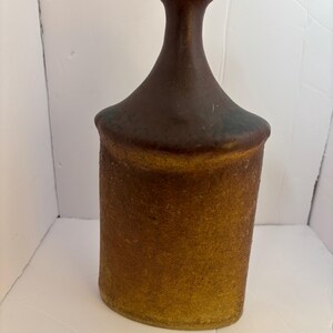 May include: A brown and tan ceramic vase with a wide mouth and a narrow neck.