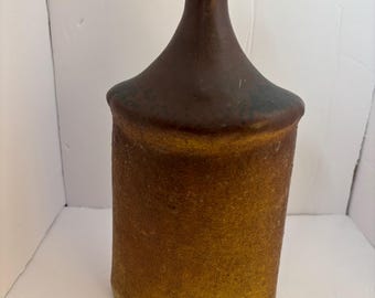 May include: A brown and tan ceramic vase with a wide mouth and a narrow neck.