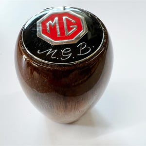 May include: A wooden gear shift knob with a chrome MG logo and the inscription "M.G.B."