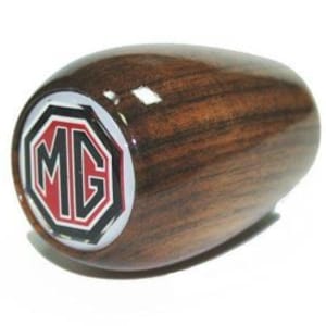 May include: A wooden gear shift knob with a black and red MG logo on a white background.