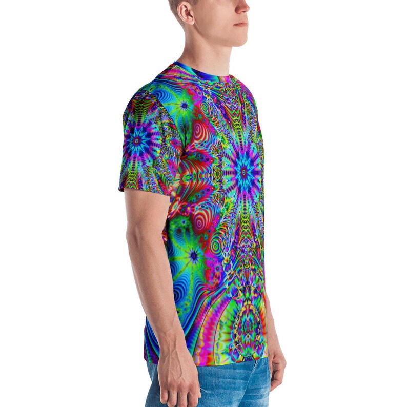 Puede incluir: Una camiseta de manga corta con un patr&oacute;n psicod&eacute;lico en tonos de azul, verde, rosa y rojo. El patr&oacute;n presenta formas giratorias y estrellas.