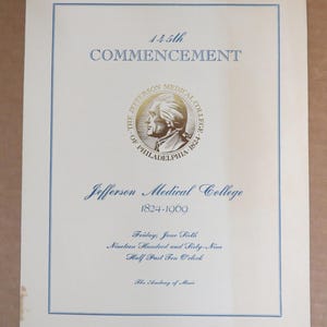 May include: Cream-colored commencement program with blue text and a blue border. The text reads "145th COMMENCEMENT" and "Jefferson Medical College 1824-1969." A circular emblem features a profile of a man. The date of the ceremony is noted.